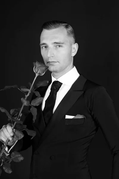 Homem de negócios com flor de rosa no fundo preto — Fotografia de Stock