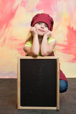 Küçük kız yemek blackboard ile şapkalı.