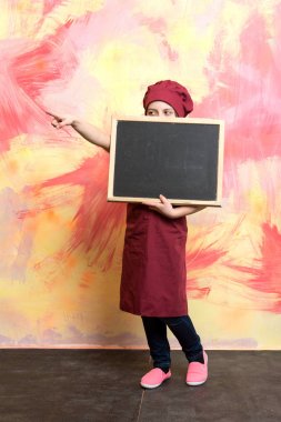 Küçük kız yemek blackboard ile şapkalı.