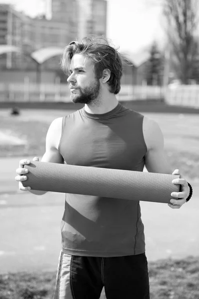 Tipo con cuerpo muscular, barba sosteniendo yoga o colchoneta de fitness — Foto de Stock