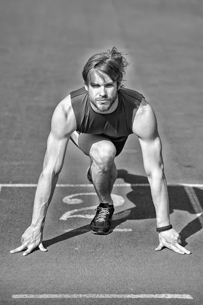 Atlético barbudo hombre con cuerpo muscular estiramiento en pista de atletismo — Foto de Stock