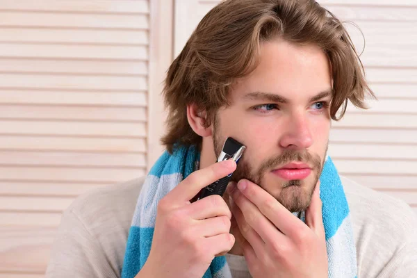 Man holds razor and starts shaving his beard