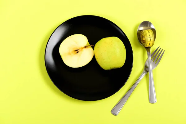 Mezze mele posizionate su piastra nera vicino a forchetta e cucchiaio — Foto Stock