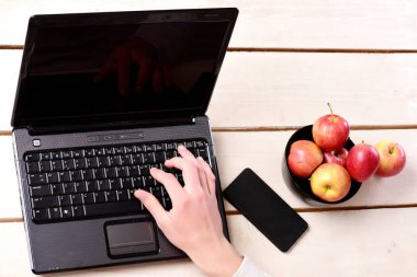 Dizüstü bilgisayar ve cep telefonu yanında elma kase. Gadget masasında