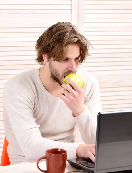 Facet używa komputera i je jabłka. Człowiek w pracy — Zdjęcie stockowe