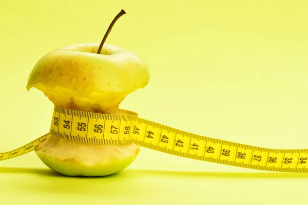 Flexibel linjal i gul färg band runt bitten äpple — Stockfoto