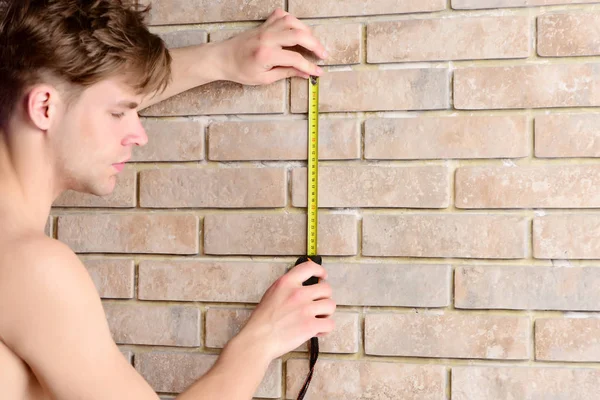 Le gars mesure le mur de briques avec la règle des constructeurs. Travailleur avec roulette — Photo