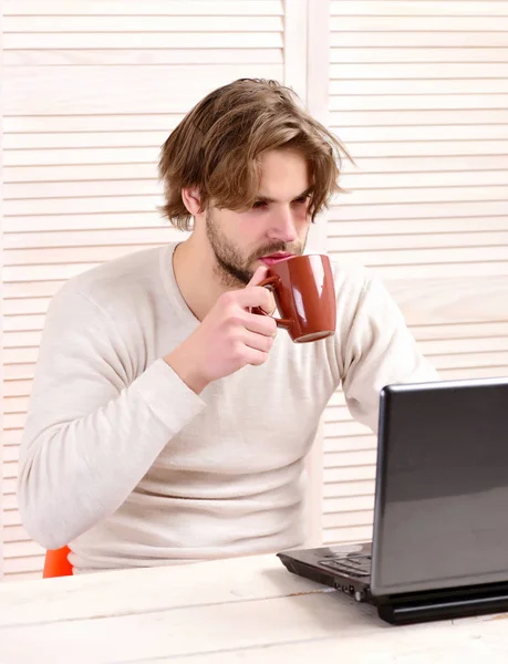 Mężczyzna w miejscu pracy z gadżetem i filiżanką herbaty — Zdjęcie stockowe