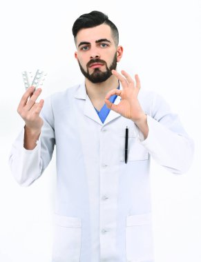 Sakallı doktor hapları tutuyor ve tamam işareti gösteriyor.