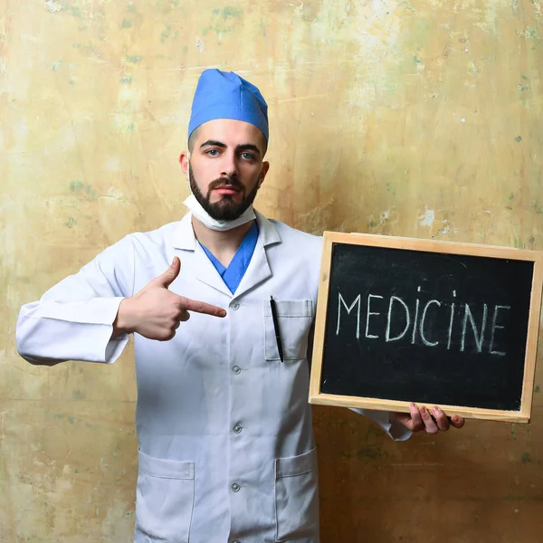 Doutor com barba apontando para pouco quadro negro com medicina palavra — Fotografia de Stock