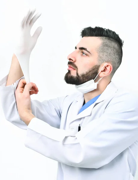 Chirurg met baard in laboratorium jas zet handschoen op — Stockfoto