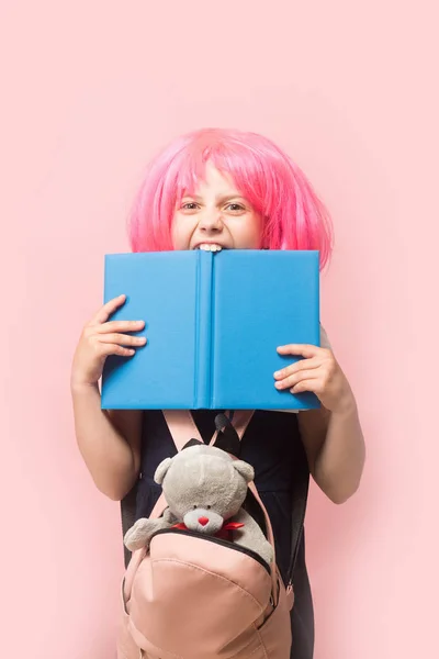 Chica con mochila y juguete muerde gran libro azul — Foto de Stock