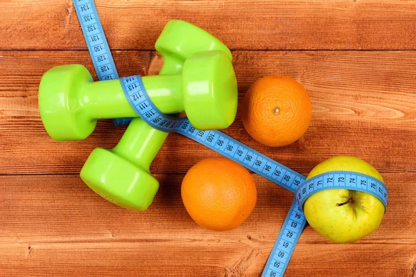 Fitness concept, dumbbells weight with measuring tape, orange and apple — Stock Photo, Image