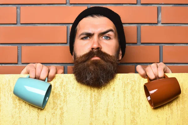 Barbudo brutal hipster caucásico con hoja de papel y tazas —  Fotos de Stock