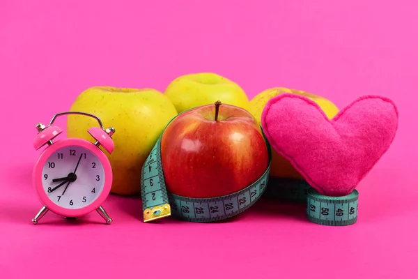 Apples, heart and alarm clock composition tied with measuring tape — Stock Photo, Image