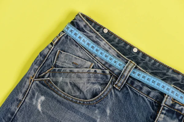 Верхняя часть джинсовых брюк на желтом фоне, крупным планом — стоковое фото