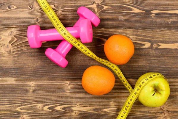 Concetto di allenamento, manubri peso con metro, arancia e mela — Foto Stock
