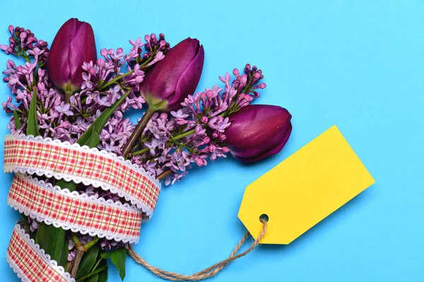 Ramo de tulipanes y flores lila y etiqueta de color amarillo brillante — Foto de Stock