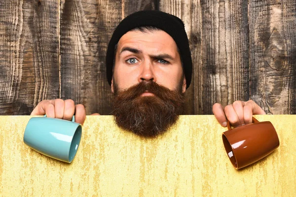 Barbudo brutal hipster caucásico con hoja de papel y tazas —  Fotos de Stock