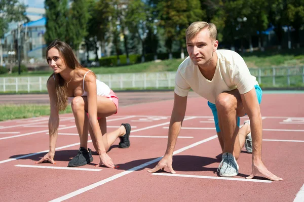 Sportpaar startet Wettkampflauf auf Arena-Bahn — Stockfoto