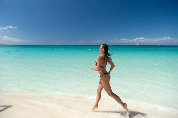 Kvinna i bikini som springer på stranden — Stockfoto