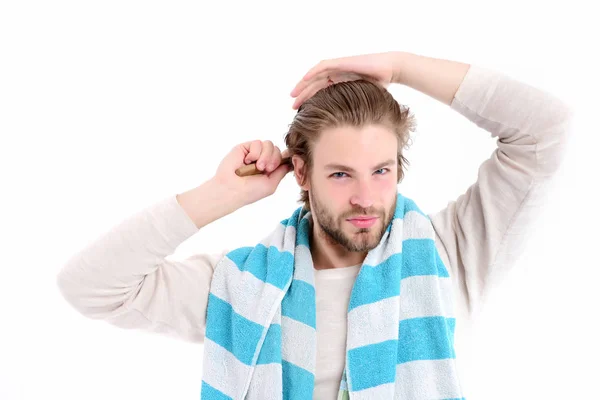 Человек с концентрированным лицом и бородой расчесывает свои мокрые волосы — стоковое фото
