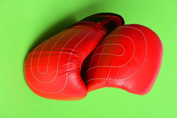 Спортивное оборудование выделено на ярко-зеленом фоне. Красные боксерские перчатки — стоковое фото