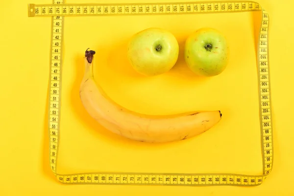 Face made of banana and apples in square