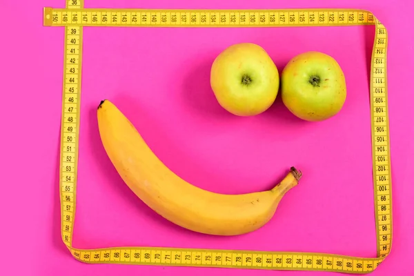 Happiness concept with apple and banana face and measuring tape — Stock Photo, Image