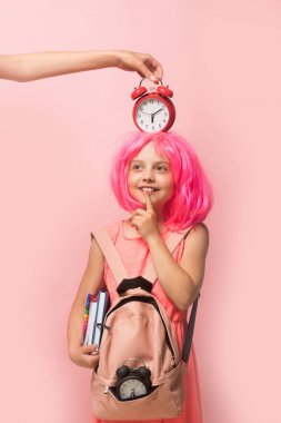 Sırt çantalı ve başında çalar saat olan çocuk.