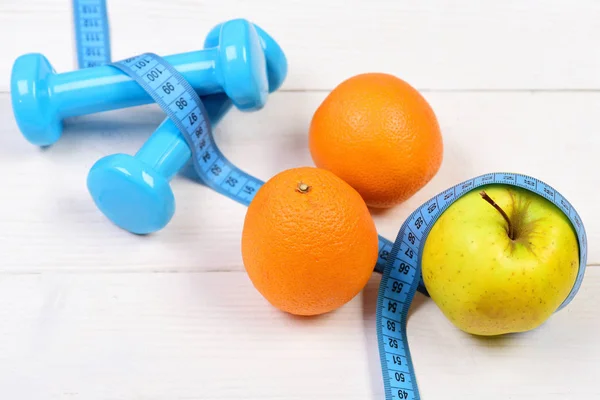 meter tape with dumbbells weight, apple, orange, diet concept