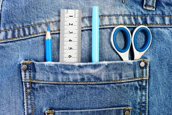 Металлические ножницы, линейка, синяя ручка и карандаш в джинсовом кармане — стоковое фото