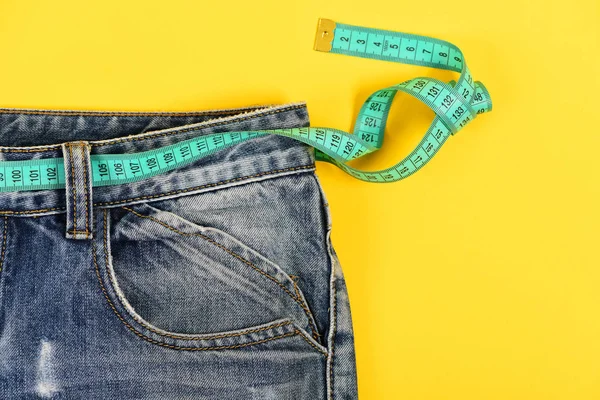 Conceito de estilo de vida saudável: jeans com fita métrica azul — Fotografia de Stock