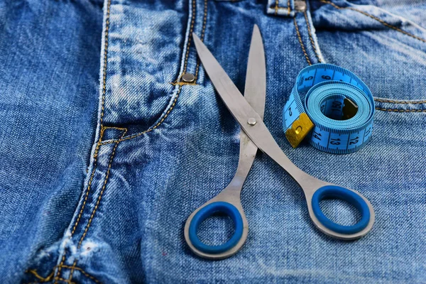Fazendo conceito de roupa: tesoura de metal e fita métrica em jeans — Fotografia de Stock