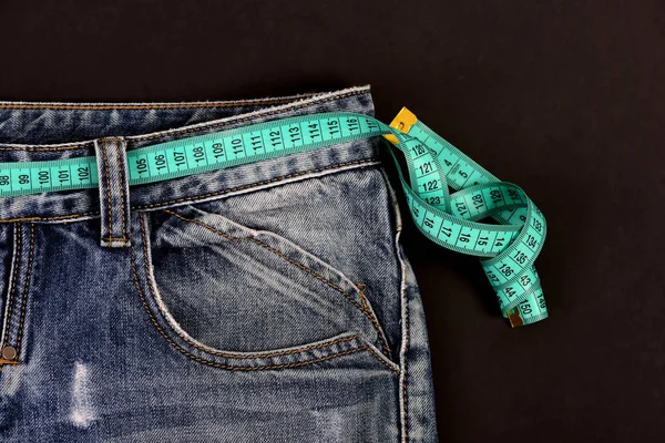 Close up de jeans com fita métrica em torno da cintura — Fotografia de Stock