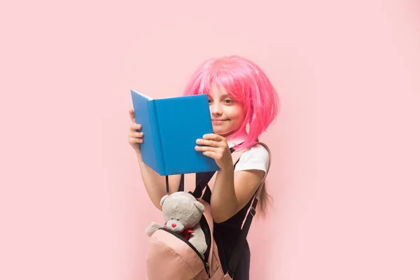 Κορίτσι με σακίδιο και toy διαβάζει το βιβλίο. Παιδί με χαμόγελο — Φωτογραφία Αρχείου