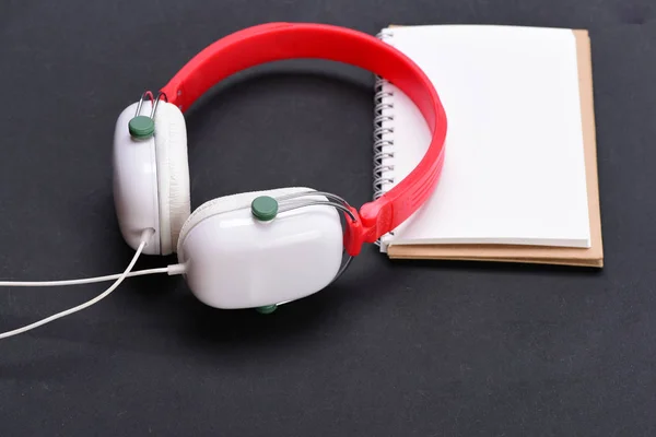 Music accessories and note taking concept. Headphones in white, red