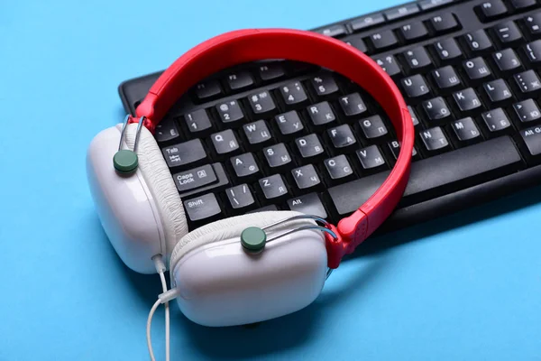 Earphones in red and white colors with computer keyboard