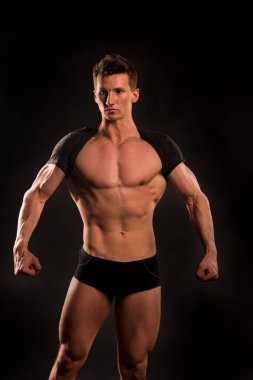 Atletik vücut geliştirmeci pantolonuyla poz.