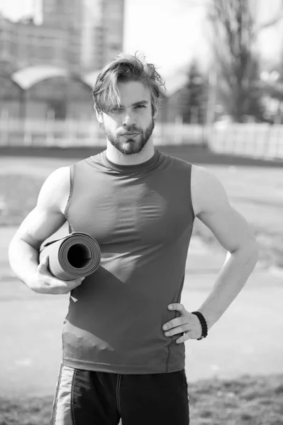 Homem muscular segurando ioga ou tapete de fitness para o exercício — Fotografia de Stock