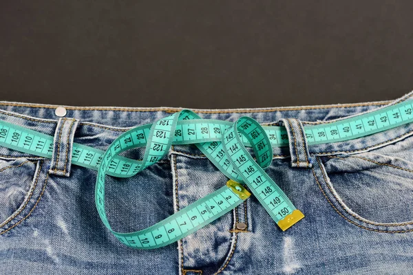 Estilo de vida saudável e conceito de dieta: medir cinto de fita no jean — Fotografia de Stock