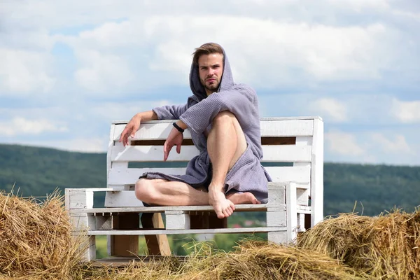 Hombre guapo adulto en albornoz de moda sentado en un banco de madera . —  Fotos de Stock