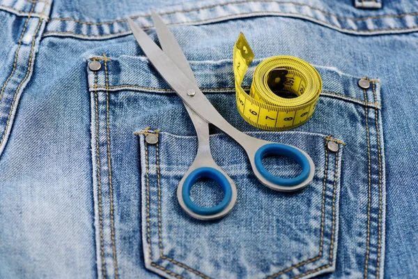 Fita métrica amarela e tesoura em bolsos traseiros de jeans — Fotografia de Stock