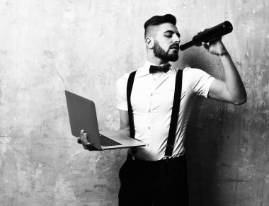 Beyaz tişörtlü adam şarap içiyor ve laptop tutar