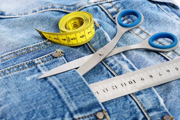 Tesoura de metal, régua e fita métrica em calças jeans — Fotografia de Stock