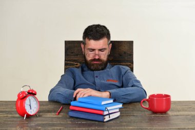 Adam uykulu yüz ile tahta masada oturur