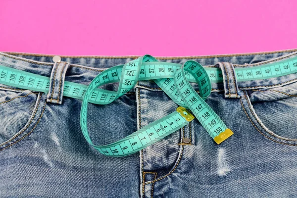 Верхняя часть джинсовых брюк на розовом в качестве концепции диеты — стоковое фото