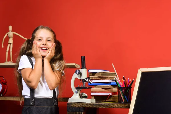 Παιδί με το σχολείο και το εργαστήριο προμήθειες σε φόντο κόκκινο τοίχο — Φωτογραφία Αρχείου