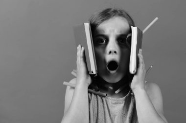 Renkli kalemler ve kalemlerle pembe elbiseli bir öğrenci.