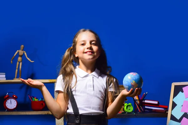 Schoolgirl with proud face holds globe model in her hand